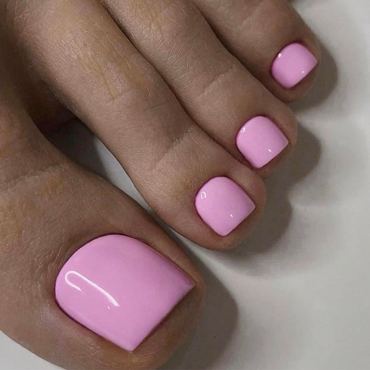 A finished pedicure with pale pink polish, short square nails, on a white background