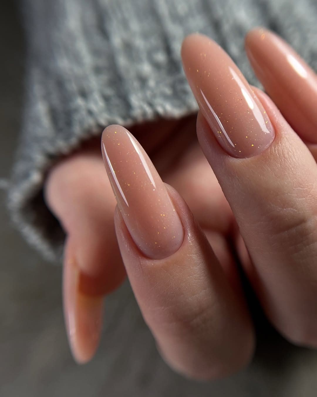 Long almond nails in a sheer peach gel with fine gold flecks