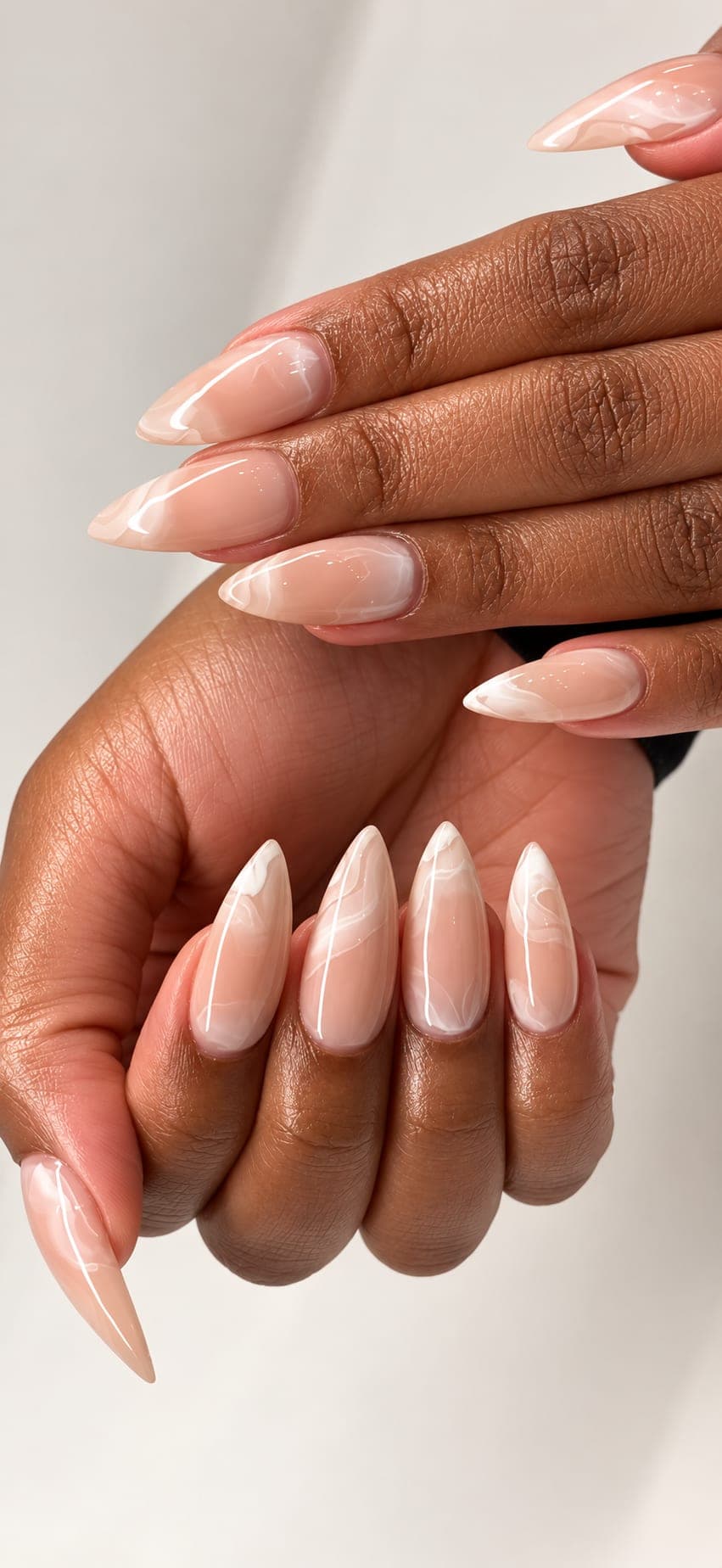 Long almond nails in a sheer pink gel with soft white marbling, on both hands
